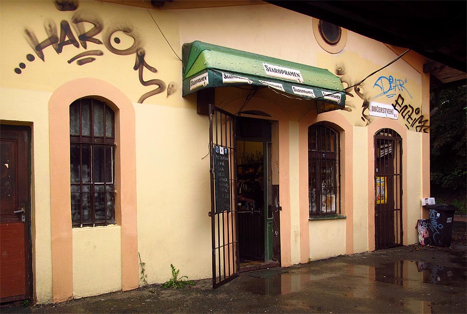 Nádražní restaurace ještě po nějakou dobu přežila ukončení provozu. V sále je zhasnuto, za výčepem ale pořád stojí vrchní… Nádražní restaurace ještě po nějakou dobu přežila ukončení provozu. V sále je zhasnuto, za výčepem ale pořád stojí vrchní…